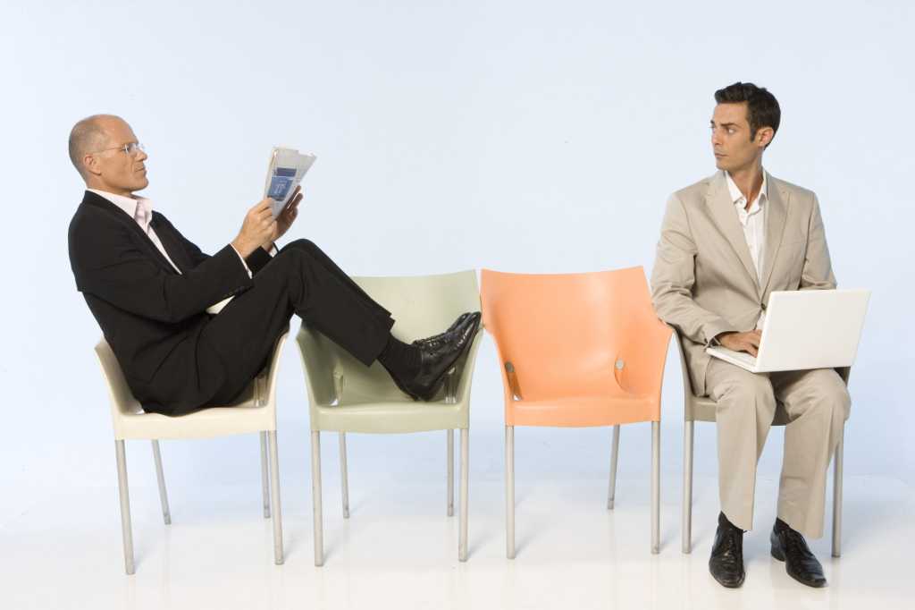two business men sitting in chairs waiting for interview