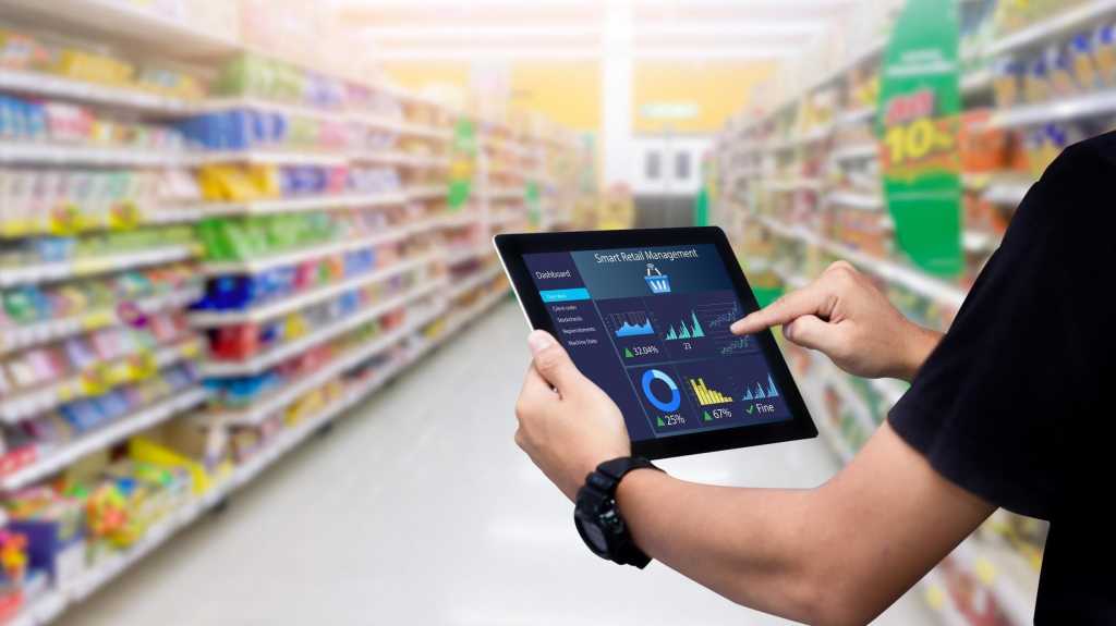 Smart Retail-Management-System.Hände, die Tablette auf unscharfem Supermarkt als Hintergrund halten