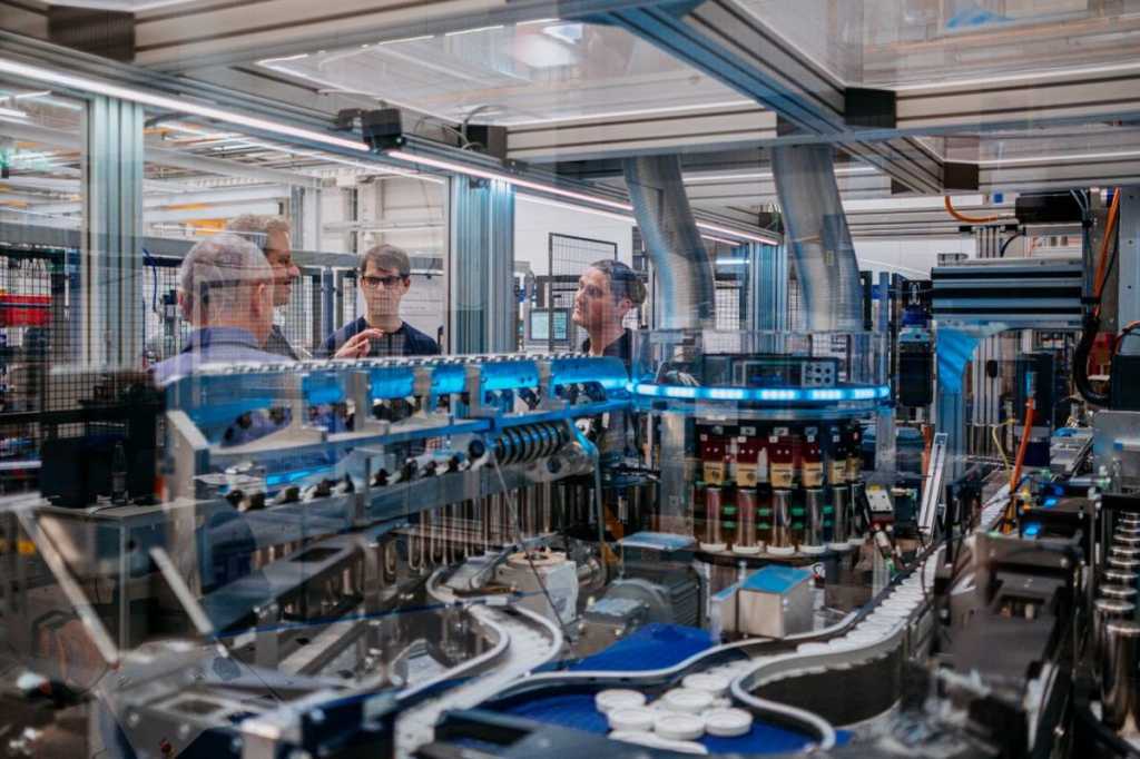 Frente a la cámara, Paul Kempt, programador de Thyssenkrupp, a la izquierda, y Marcus Schoenherr, ingeniero de Thyssenkrupp, con la máquina de pruebas de células de baterías de vehículos eléctricos.