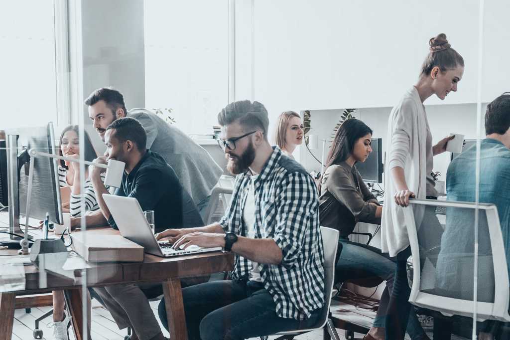 Group of people working together and collaborating in a shared office workspace.