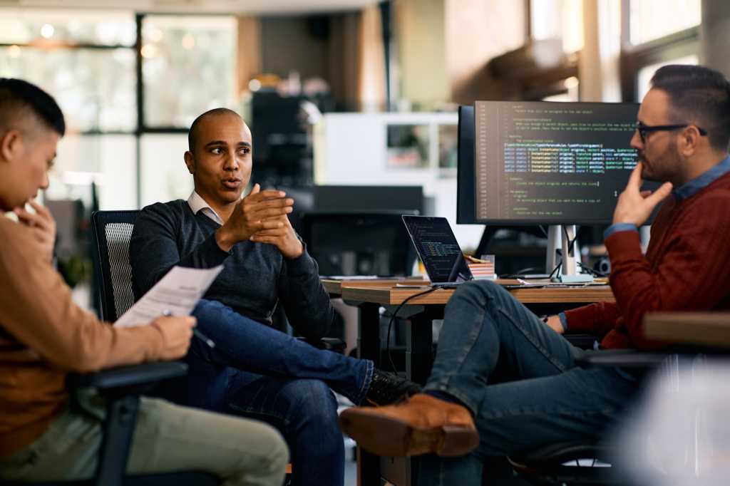 Group of computer programmers talking while working at IT office