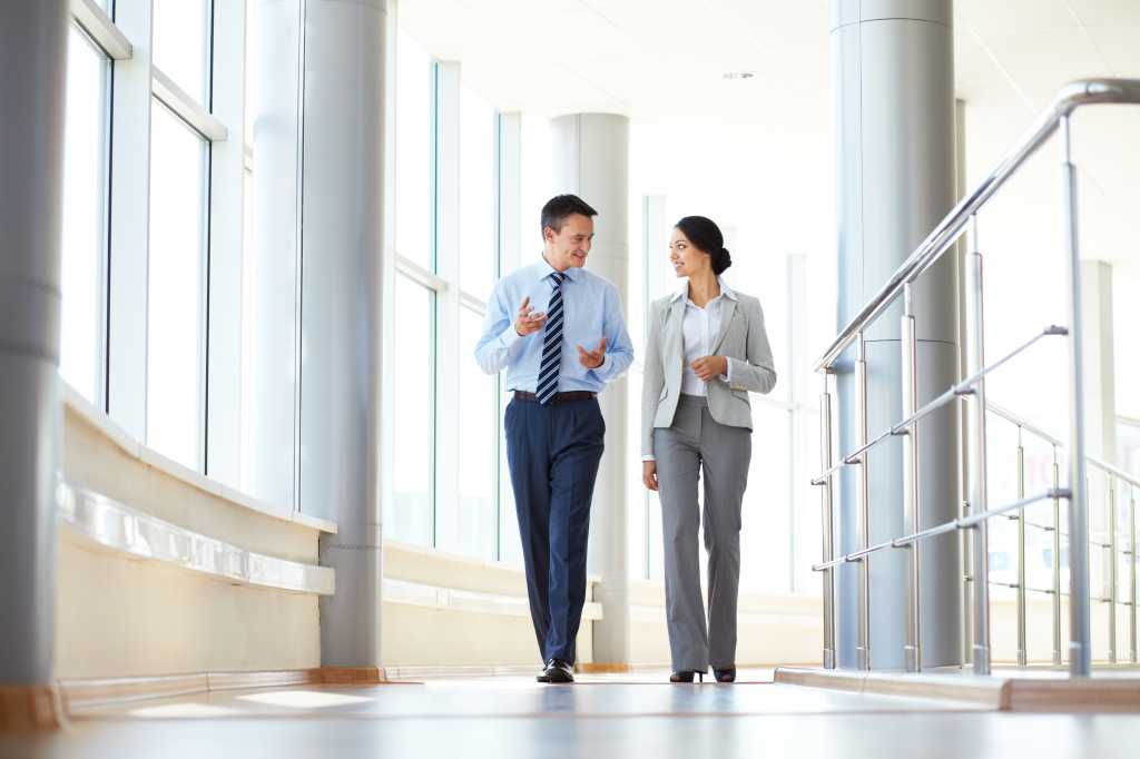 Confident business partners walking down in office building and talking