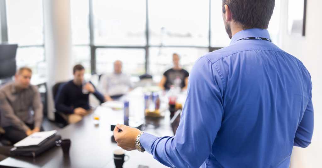 Business man making a presentation at office. Business executive delivering a presentation to his colleagues during meeting or in-house business training, explaining business plans to his employees.