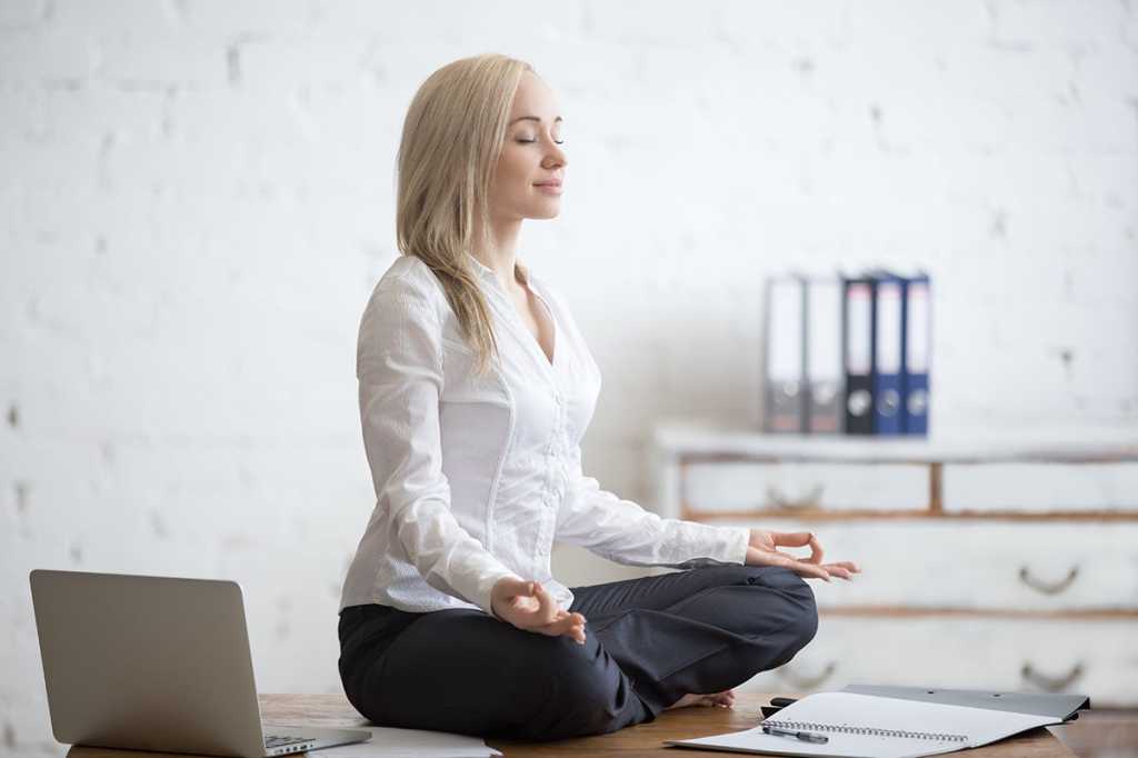 businesswoman meditates on her desk - workplace meditation - relaxation - satisfaction - happiness