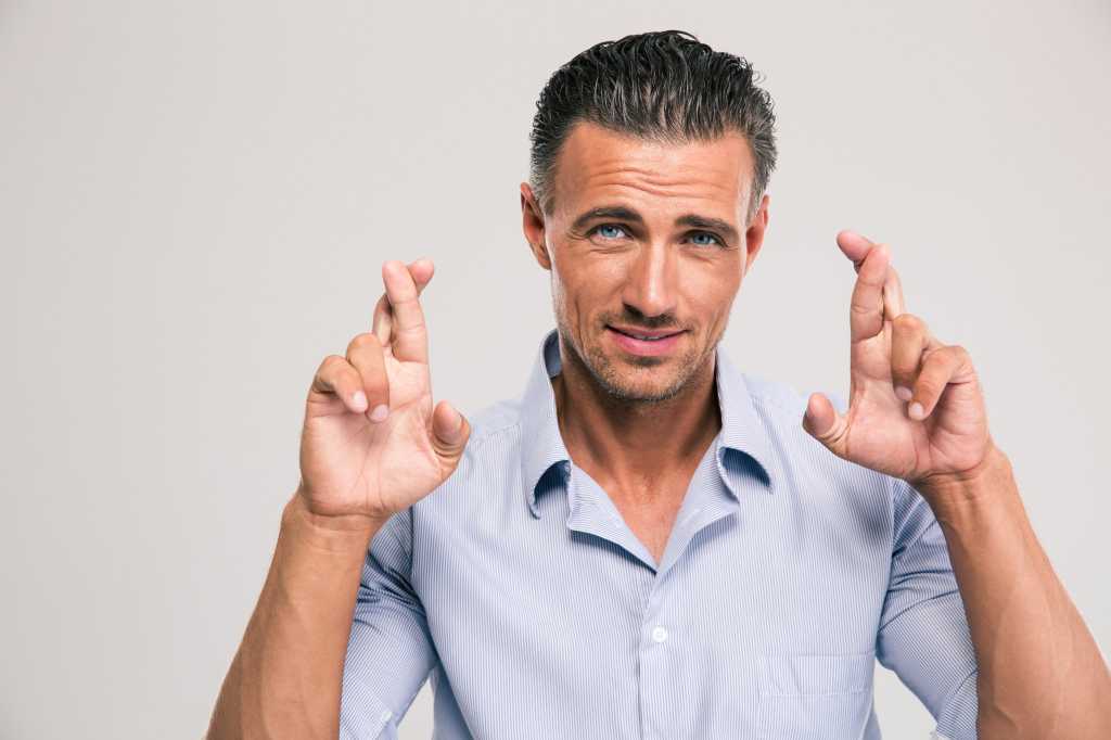 Man standing with fingers crossed hopeful