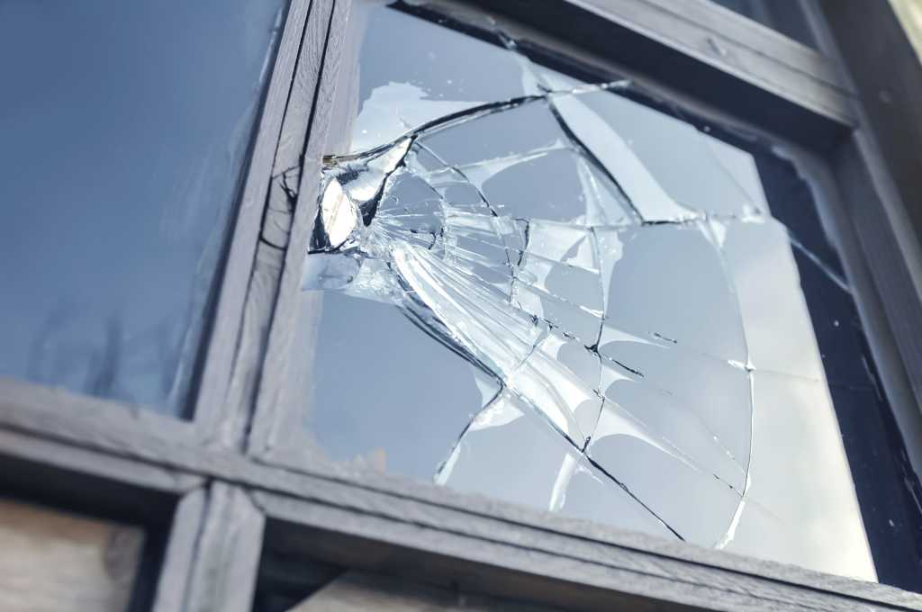 Broken pane of glass in window with sky reflecting