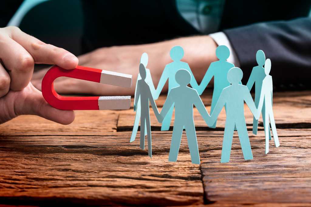 Recruiter attracts leads > Using a horseshoe magnet on a group of figurines.