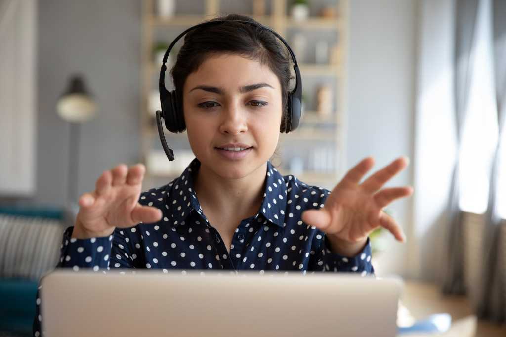 A woman with a headset is engaged in discussion via video conferencing.