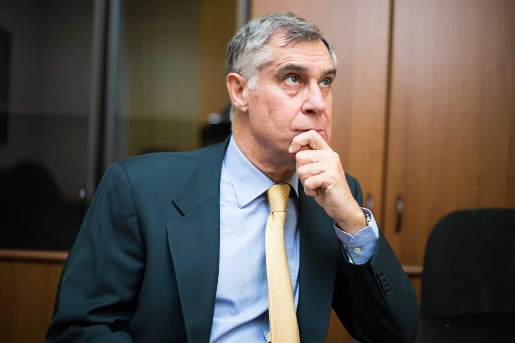Pensive mature businessman looking up with concentration and writing in his paperwork at office
