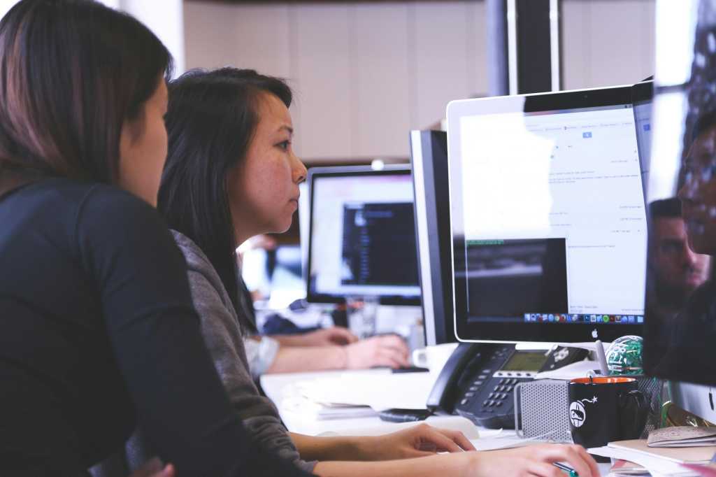 Two women programmers looking at a computer monitor