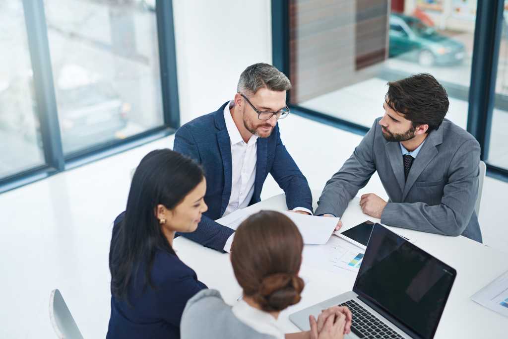 Laptop, meeting and business people in office with teamwork for finance stock market planning. Collaboration, technology and group of financial advisors working on company budget in workplace.