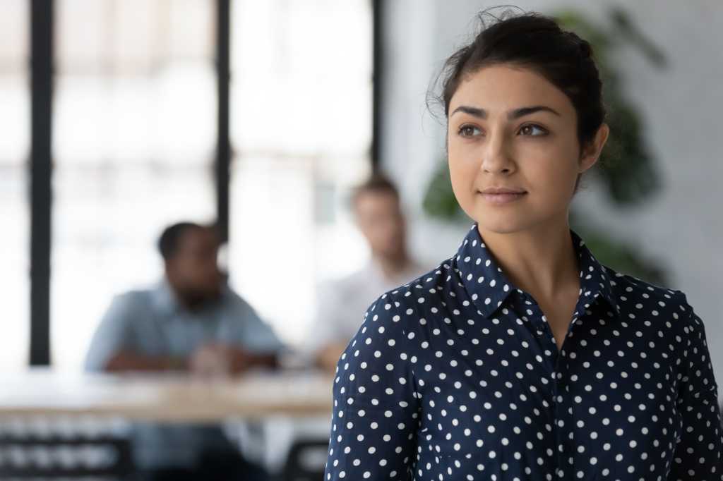 Dreamy young Indian female employee look in distance thinking or pondering, thoughtful happy millennial biracial woman worker plan consider future career opportunities, business vision concept