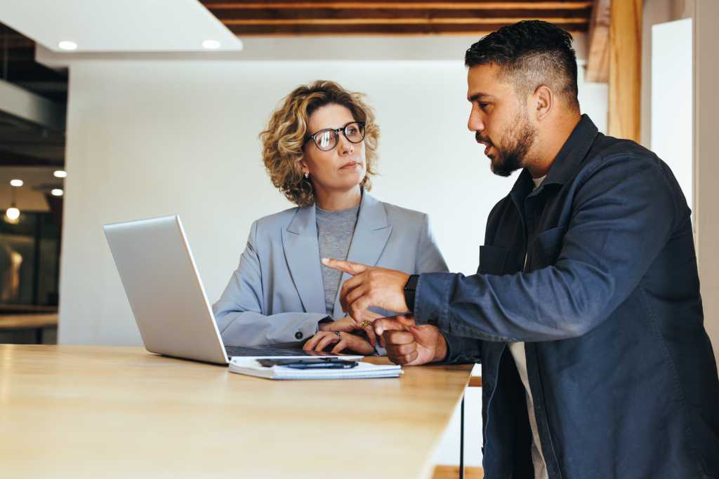 Colleagues discussing a business project in an office. Professional business people having a meeting. Collaboration and teamwork between two business colleagues.