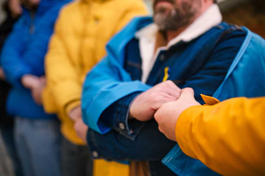 Cropped shot of protestors with Ukrainian blue and yellow ribbons and flags protesting against war in Ukraine in street