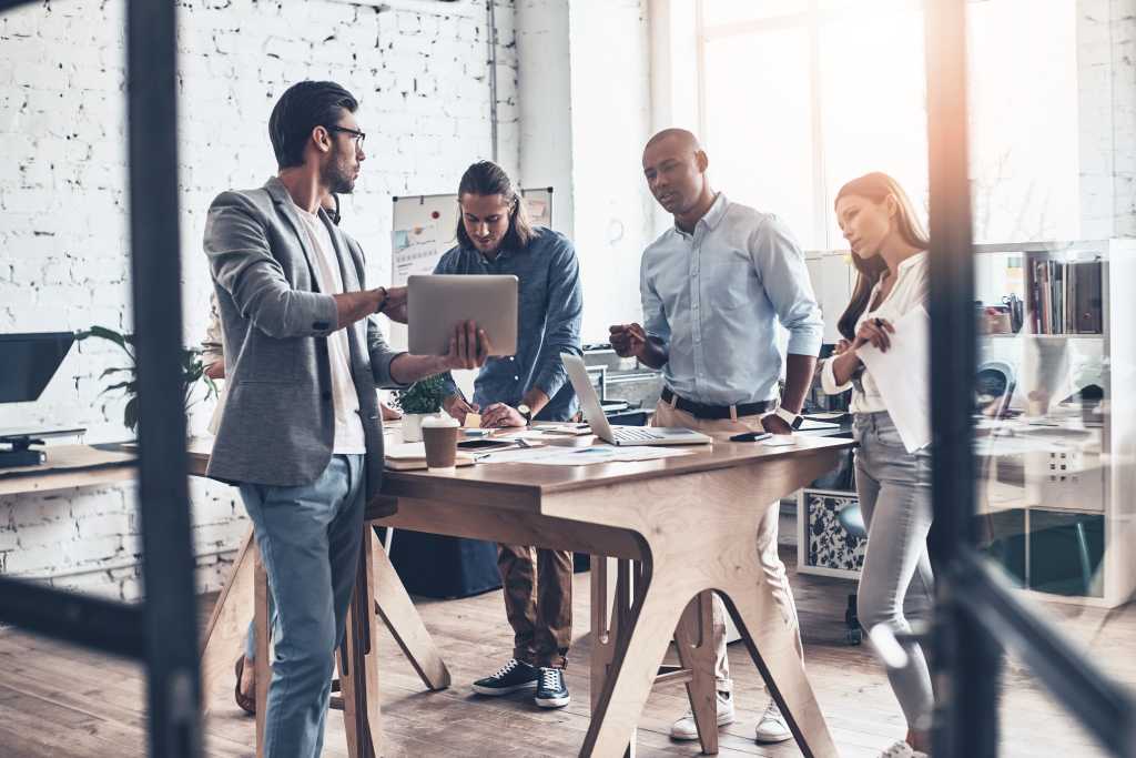 Sharing new ideas. Group of young modern people communicating together while working in the board room