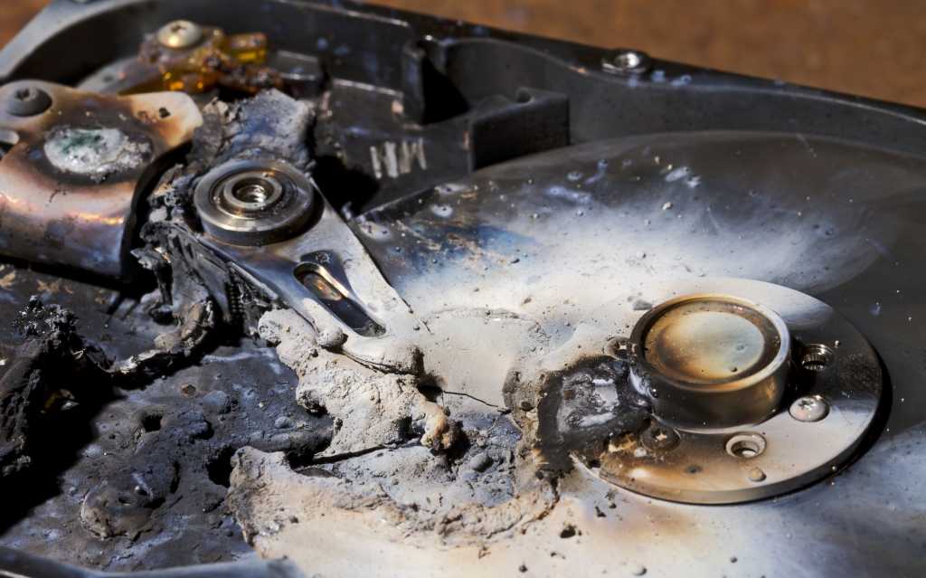 destroyed hard drive in close up view. The read write head is melted