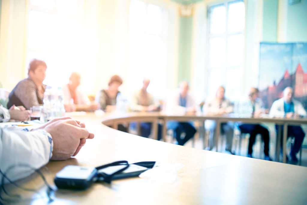 People at a round table discuss different issues. Focus on hand