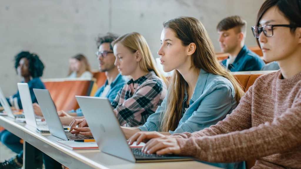Studenten, die im Hörsaal an Laptops arbeiten, 16:9