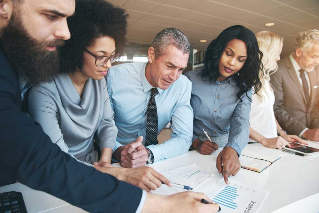 Diverse group of professionals discussing a business strategy and diagram in office together.