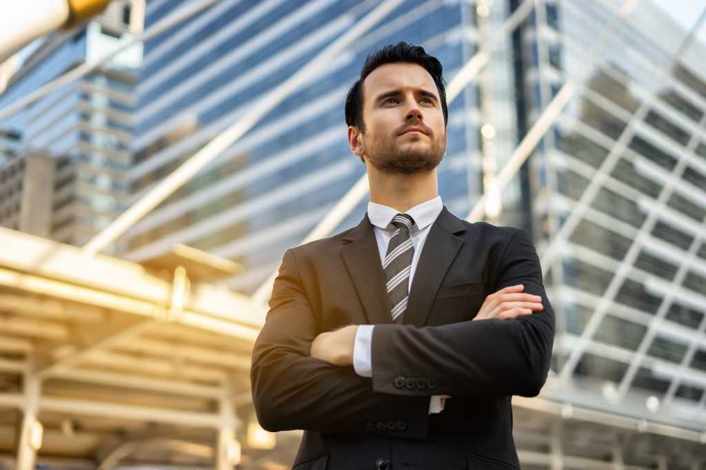 Serious man employer waiting for start interview or startup meeting, male confident CEO expects a partner sign an agreement, Smart handsome successful elegant formal suit standing with crossed arms