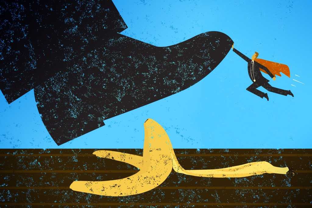 A shoe about to step on a banana peel, stopped by a small superhero.