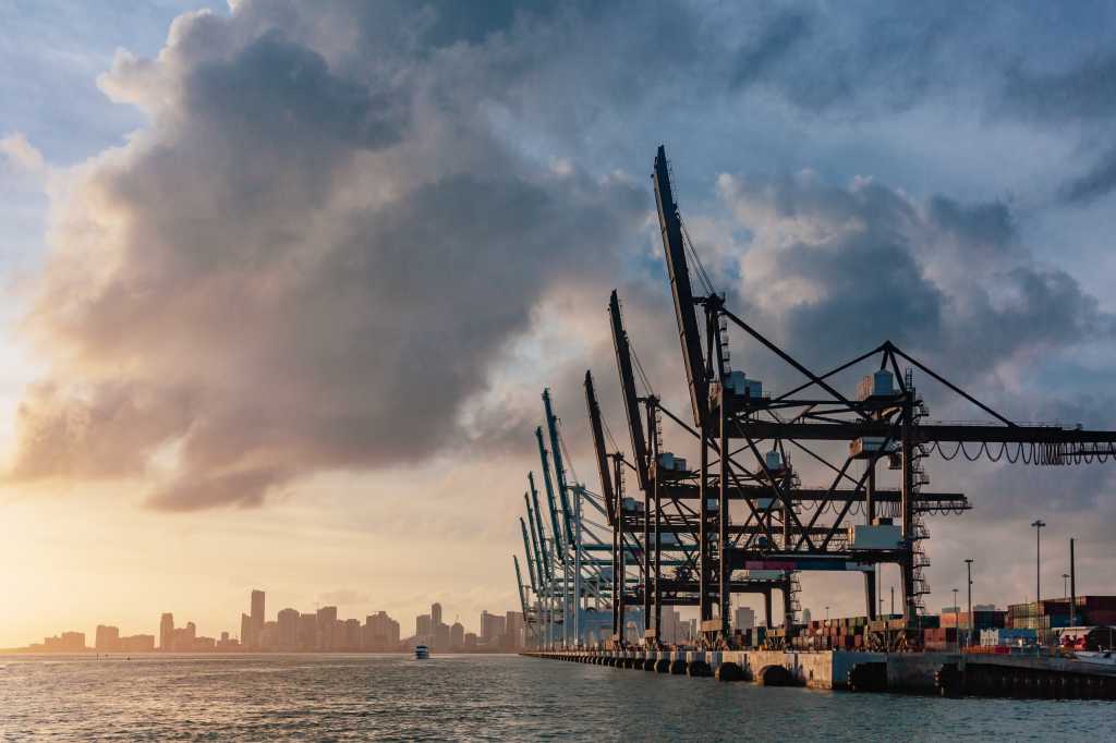 View of cranes of the port of Miami and skyline of downtown Miami at sunset, in Florida, USA