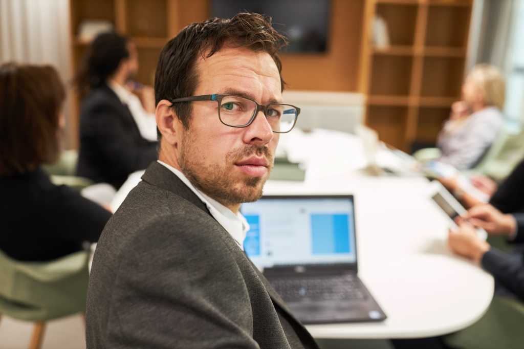 Business man as a skeptical manager or consultant using laptop computer in a meeting