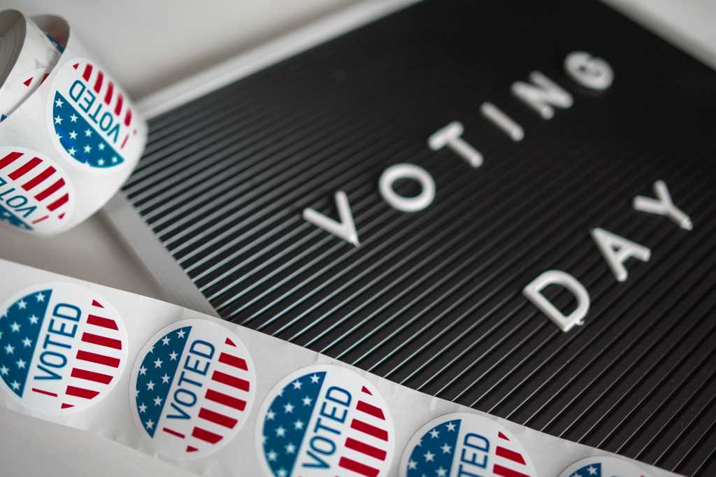 A roll of 'I Voted' election stickers, along with a 'Voting Day' sign.