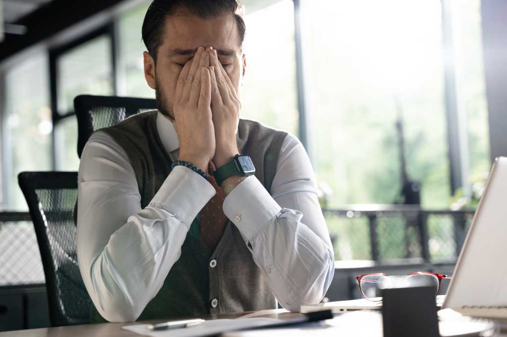 Feeling exhausted. Frustrated middle-aged beard man massaging his nose and keeping eyes closed while sitting at his working place in office