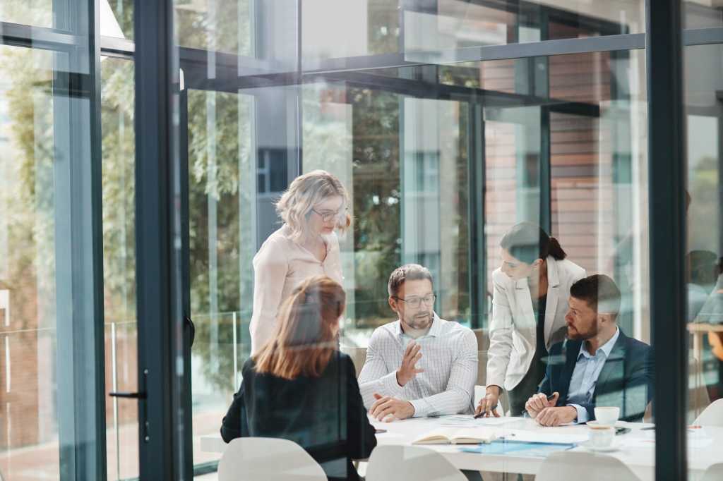 Window, business people or planning in meeting for paperwork, teamwork or collaboration together. Shareholders, investor or executive director speaking in discussion for feedback, review or project
