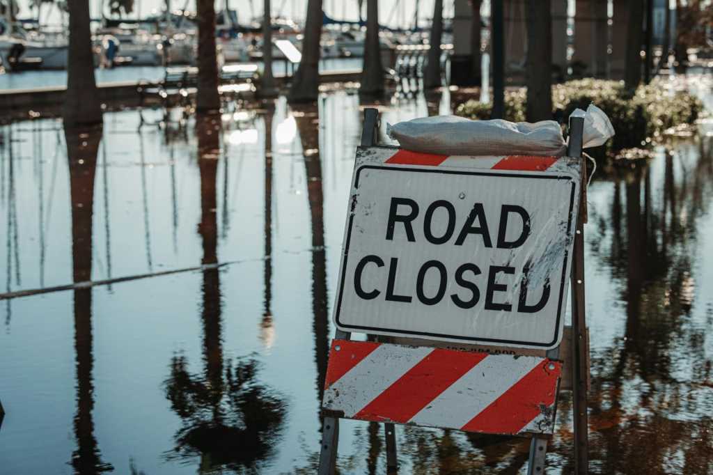 road closed sign with flooded road in background