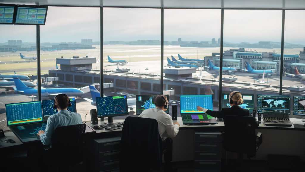 Diverse Air Traffic Control Team Working in a Modern Airport Tower. Office Room is Full of Desktop Computer Displays with Navigation Screens, Airplane Departure and Arrival Data for Controllers.