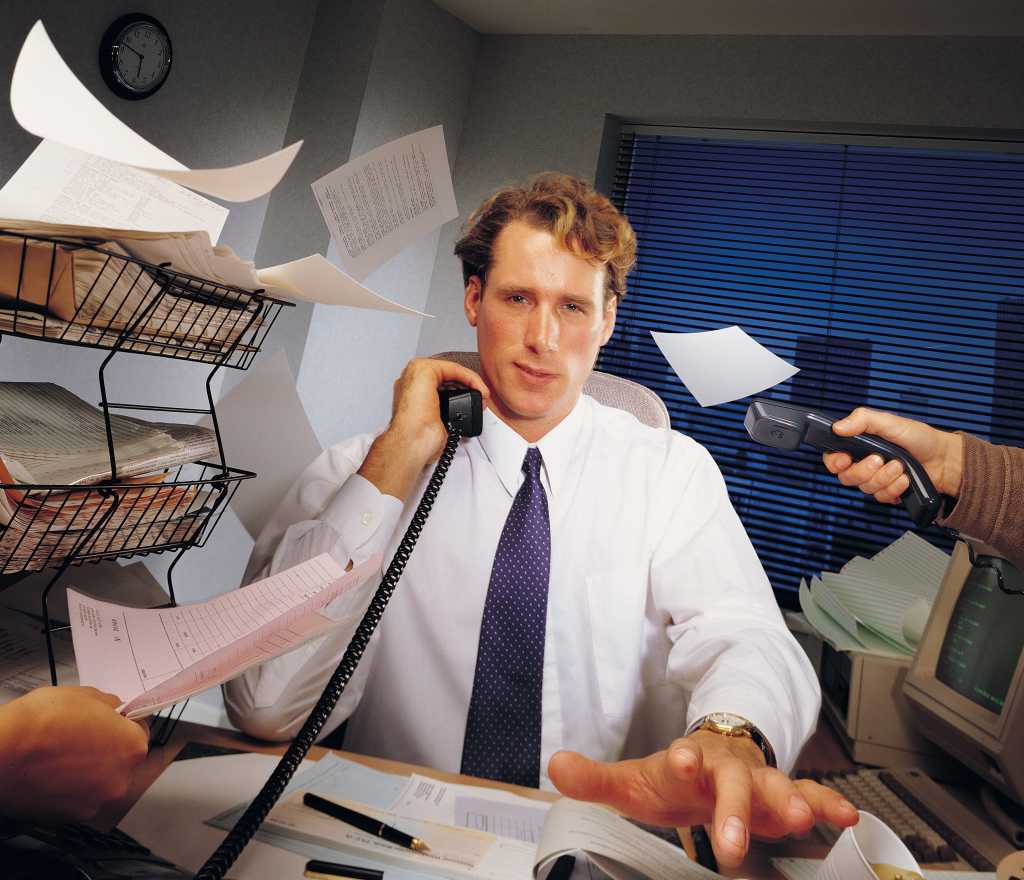 Efficiency - a busy man at his desk, surrounded by chaotic paperwork