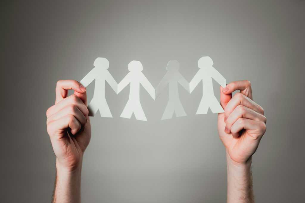 manos con un papel con forma de personas
